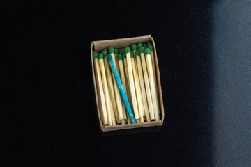 homosexuality concept: one blue match in a box with ordinary matches, black background
