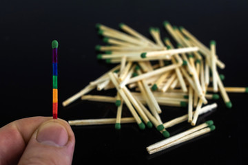 homosexuality concept: an unusual match of the iridescent color of LGBT symbolism opposite to ordinary matches