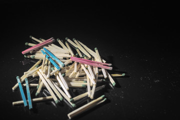 homosexuality concept: several pairs of blue and pink matches in front of a pile of ordinary matches, black background, short focus, limited lighting, toning