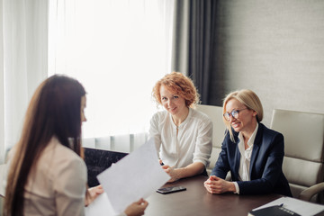 Group of two female corporate mentors check the knowledge of the woman trainee at the end of the trial period