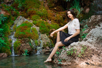 Fototapeta premium Beautiful dark haired girl posing in river with green plants. Beauty, fashion. Spa, healthcare. Tropical vacation. Natural pool.