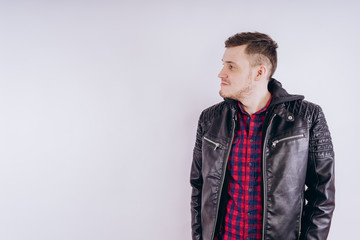 Man in trendy jacket on white background. Portrait of young male in leather jacket zipping up and smiling at camera on white background