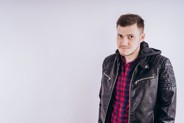 Obraz premium Man in trendy jacket on white background. Portrait of young male in leather jacket zipping up and smiling at camera on white background
