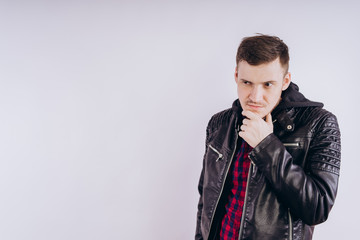 Man in trendy jacket on white background. Portrait of young male in leather jacket zipping up and smiling at camera on white background