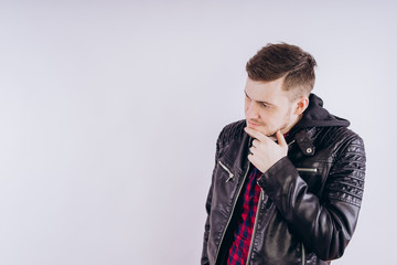 Man in trendy jacket on white background. Portrait of young male in leather jacket zipping up and smiling at camera on white background