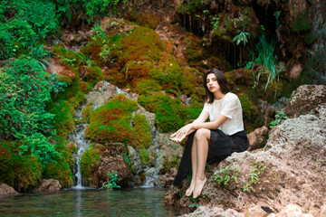 Fototapeta premium Beautiful dark haired girl posing in river with green plants. Beauty, fashion. Spa, healthcare. Tropical vacation. Natural pool.