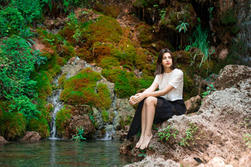 Beautiful dark haired girl posing in river with green plants. Beauty, fashion. Spa, healthcare. Tropical vacation. Natural pool.