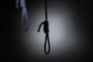 blurred shadow of the loop of the gallows on the light wall, darkness, reduced color