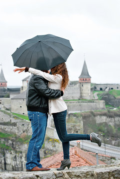 A couple hugging against the background of the fortress. Kiss under an umbrella.