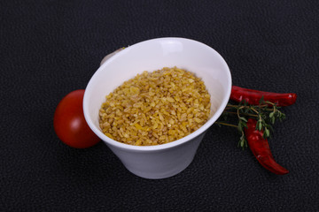 Raw bulgur in the bowl with tomatoes and garlic