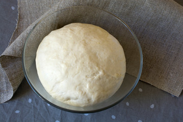 Fresh raw dough in a glass bowl.