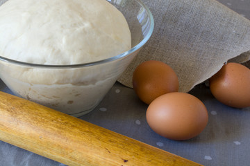 Fresh raw dough in a glass bowl with eggs.