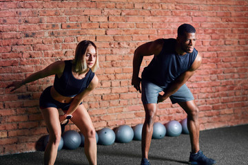 Young caucasian woman athlete working out with kettlebells with the help of personal trainer during...