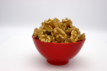 Walnut Kernels In Red Bowl (Other Names: Juglans Regia, Persian Walnut, English Walnut, Circassian Walnut). Isolated Image On A White Background