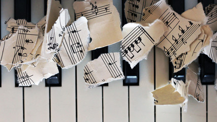 Torn musical notes, pieces of paper on piano