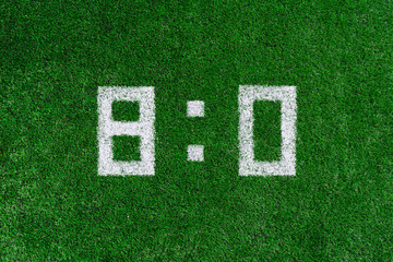 Football score 8:0.White numbers eight and zero are drawn on the green grass,creative scoreboard
