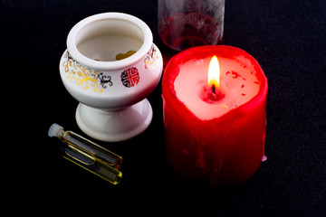 red scented candle, white lamp and oil bottles