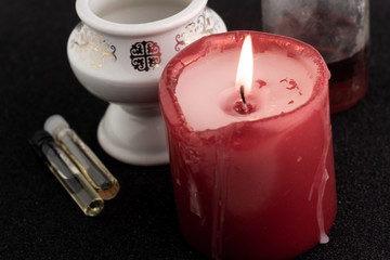 red scented candle, white lamp and oil bottles