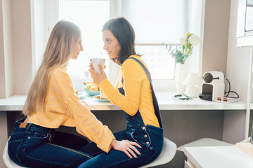 two pretty girls having a drink at home in the morning. close up photo. relationship concept
