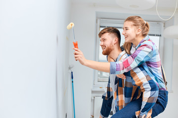 Young couple painting walls and having fun while renovating their new house.
