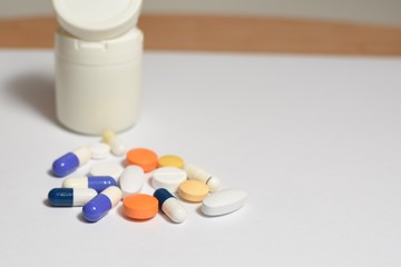 A close-up photo of various medical pills and capsules spilt on white background