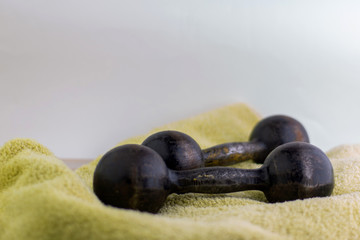 fitness and bodybuilding: 2 black metal dumbbells on a towel, short focus