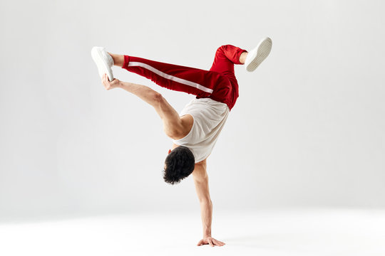 Isolated Korean hip hop male break dancer dancing on white background, performing air split stout element of downrock breakdance