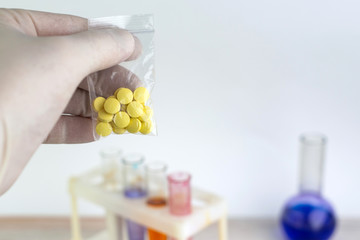 problem of synthetic psychotropics: a person shows a sample of a new drug above the table with other samples, short focus