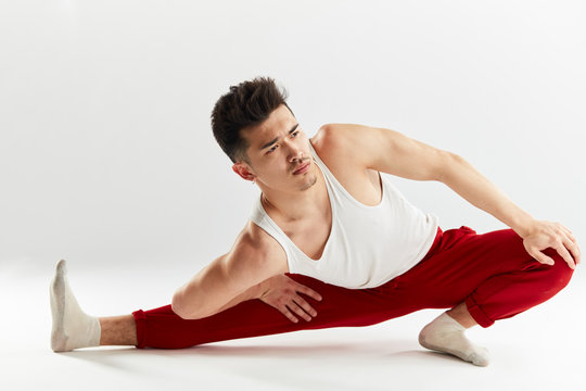 Asian Man Gymnastic In Red Sports Sweatpants Warming Up Isolated Studio On White Background