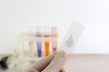 study of synthetic psychotropics: a person shows a glass slide with a sample of an unknown powder above the table with other samples, short focus
