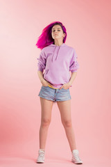 awesome girl in trendy clothes with blowing purple hair isolated on the pink background. full length photo.careless life