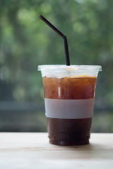 Iced americano coffee on wood table with nature background