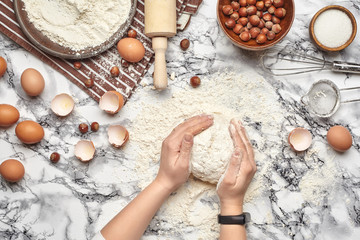 Fototapeta na wymiar Close-up shot. Top view of a baker cook place, hands are working with a raw dough on the marble table background.