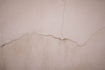 Beige stucco wall crackle surface. Light beige textured background. Grunge texture. Rough weathered backdrop