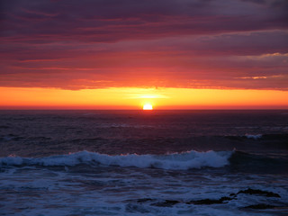 Sun on horizon at sunset on the beach with beautiful vivid orange sky.