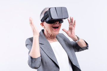 Amazed senior business woman trying out VR (virtual reality) goggles for the first time, immersed by the interactive experience on her display