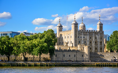 View of the Tower of London, a castle and a former prison in London, England, from the River Thames. The Tower of London, today a museum, is a fortified complex that includes multiple buildings - obrazy, fototapety, plakaty