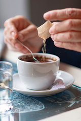 A senior old woman adding sugar to her coffee, mix and stir to blend
