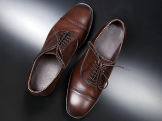 Classic men's brown Oxford shoes on dark background