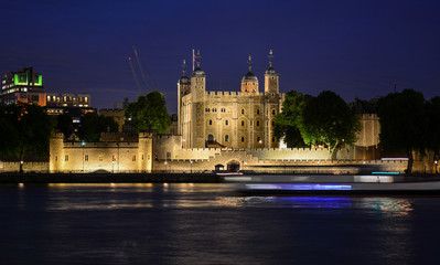Fototapeta na wymiar The Tower of London, an old castle and a museum where crown jewels are stored, seen from the River Thames at night. The famous fortress is located on the Tower Hill in the center of London, England
