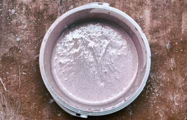 A bucket of primer with a paintbrush. Preparation of the wall for painting.