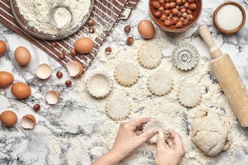 Close-up shot. Top view of a baker cook place, hands are working with a raw dough on the marble table background.