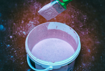 A bucket of primer with a paintbrush. Preparation of the wall for painting.