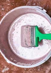 A bucket of primer with a paintbrush. Preparation of the wall for painting.