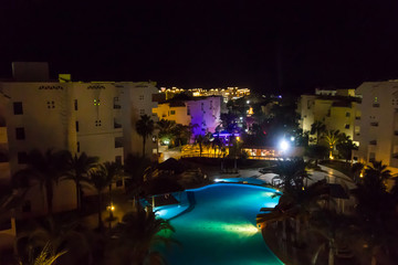 Night view of the modern blue water swimming pool in tropical resort. View from above