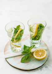 Infused water in two glasses with lemon, cucmber and basil