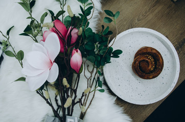 Top view of flower and cinnamon bun on white dish