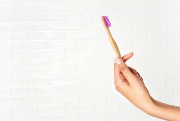 Close up of woman's hand holding bamboo toothbrush