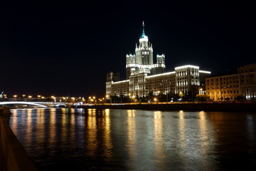 Obraz premium View of the skyscraper Kotelnicheskaya Embankment Building (Moscow) across the Moskva-river with illumination and with colorful night street lighting reflected in the water