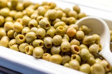 Close up of fresh and organic pitted green olives on a luxury Greek buffet with a serving spoon